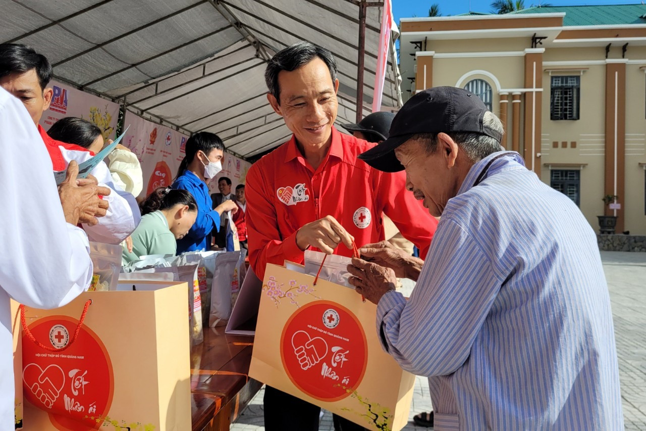 Ông Lê Tấn Minh - Chủ tịch Hội Chữ thập đỏ tỉnh trao quà cho người dân tại phiên chợ Tết nhân ái. Ảnh: M.L
