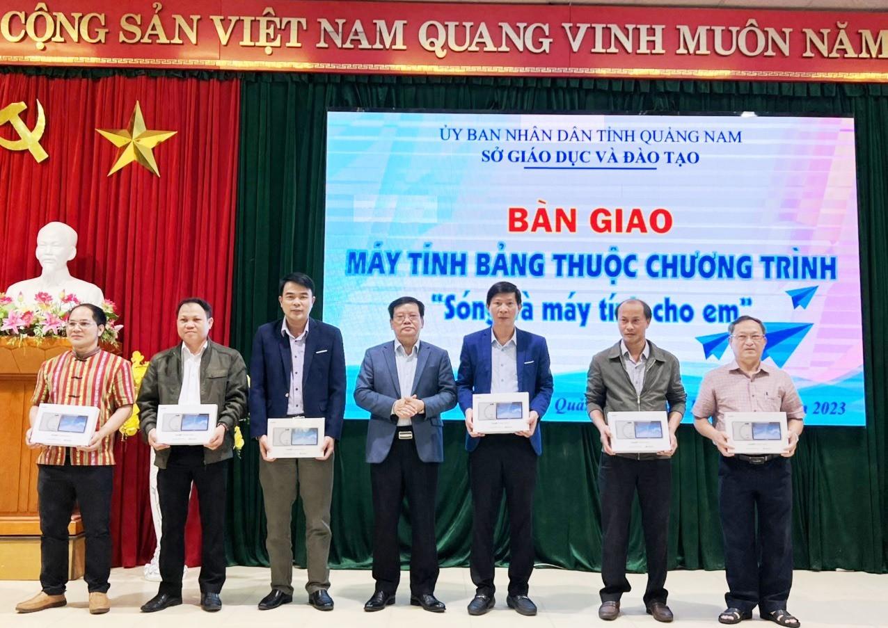 Ông Thái Viết Tường – Giám đốc Sở Giáo dục và Đào tạo tỉnh Quảng Nam (đứng giữa) bàn giao máy tính bảng cho các đơn vị. Ảnh: VT