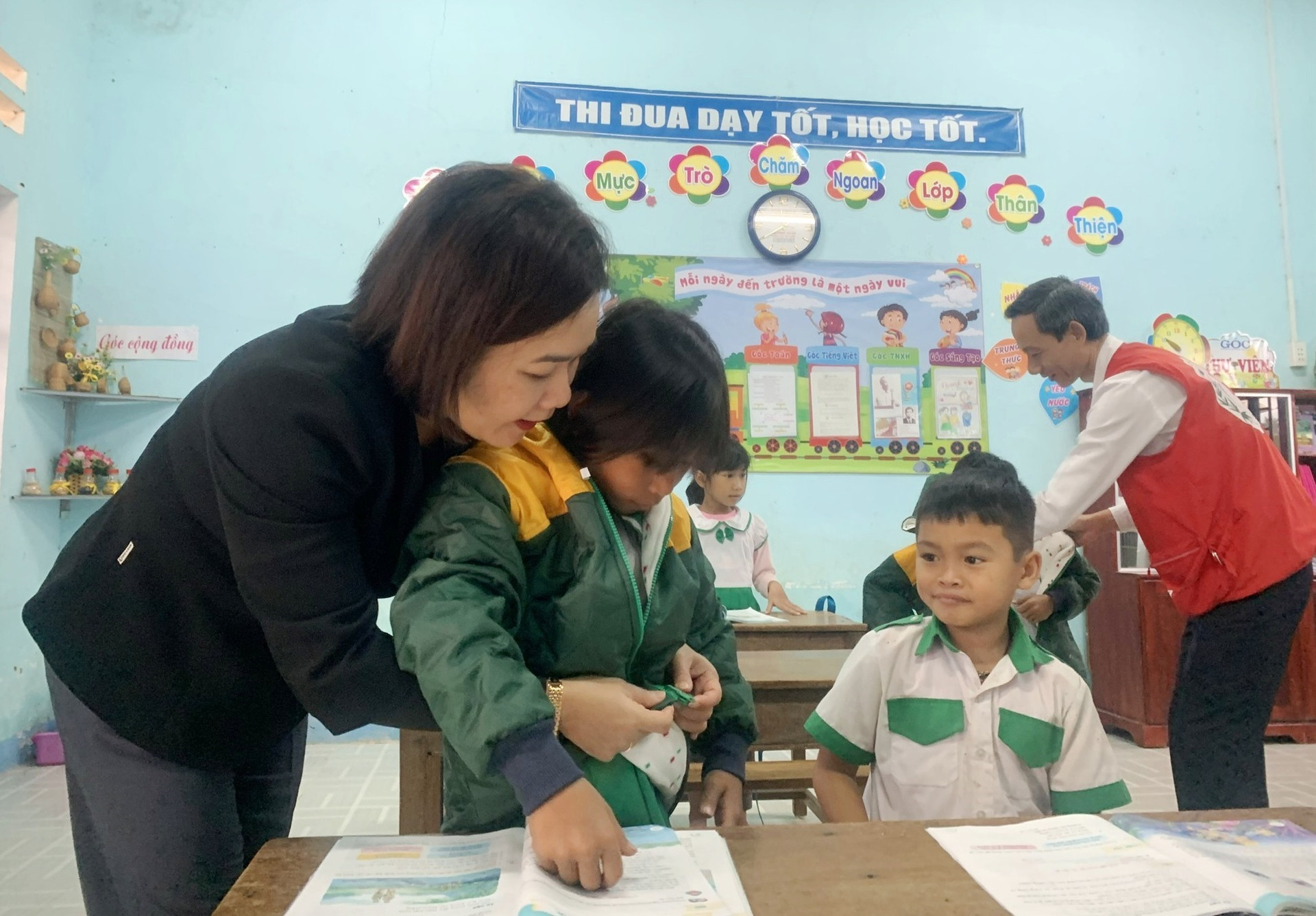 Ủy viên BTV - Trưởng Ban dân vận Tỉnh ủy Huỳnh Thị Thùy Dung mặc áo ấm cho các em nhỏ làng Cao Sơn (Bắc Trà My). Ảnh TÚ VÂN