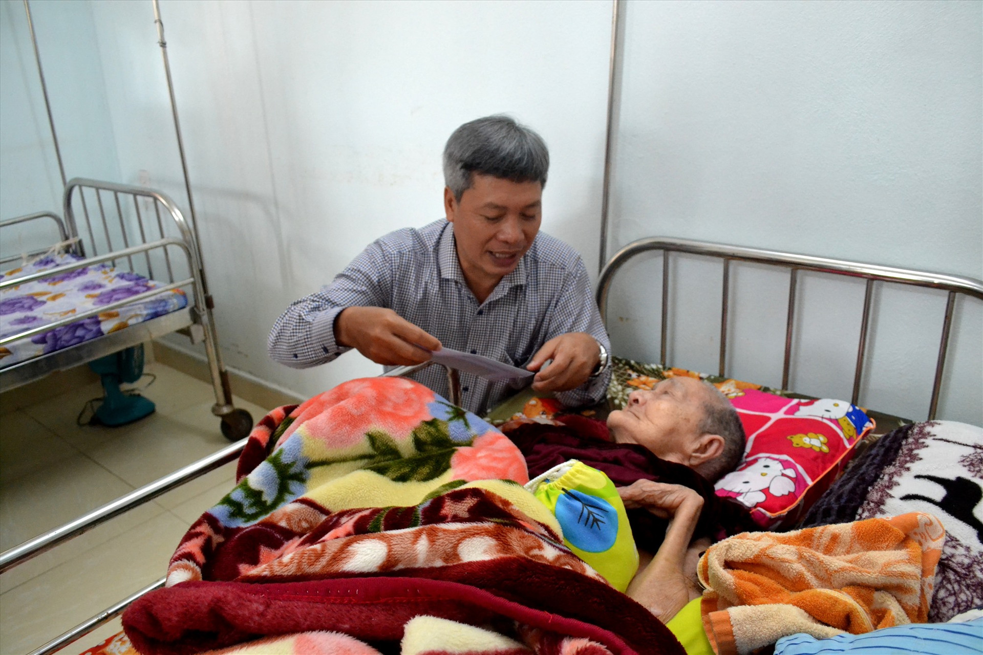 Phó Chủ tịch UBND tỉnh Hồ Quang Bửu tận tình hỏi thăm, tặng quà và chúc tết người có công ở Trung tâm Nuôi dưỡng, điều dưỡng thương, bệnh binh và người có công Quảng Nam. Ảnh: Q.VIỆT