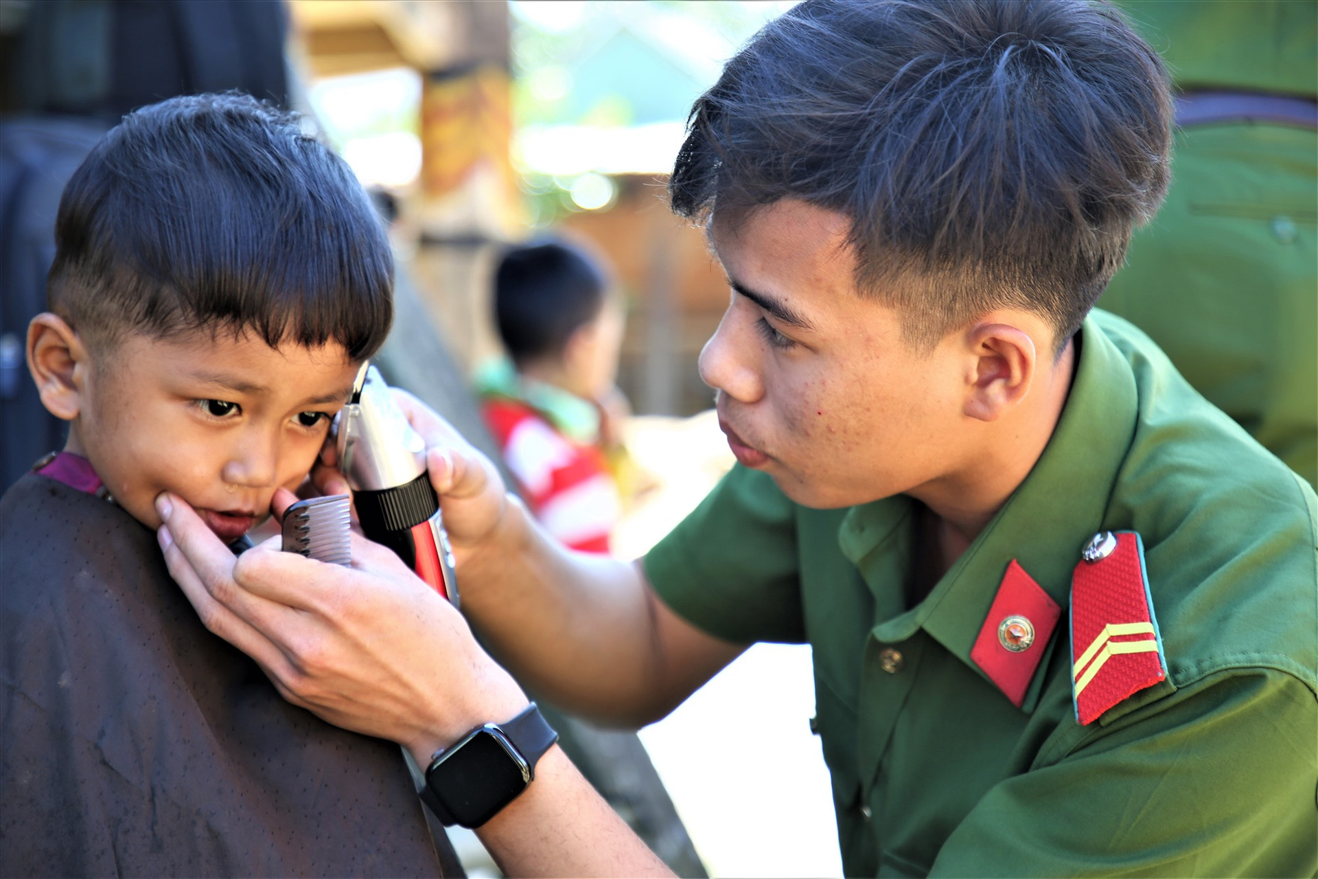 Một nam chiến sĩ cắt tóc miễn phí cho trẻ em vùng cao Tây Giang. Ảnh: A.N