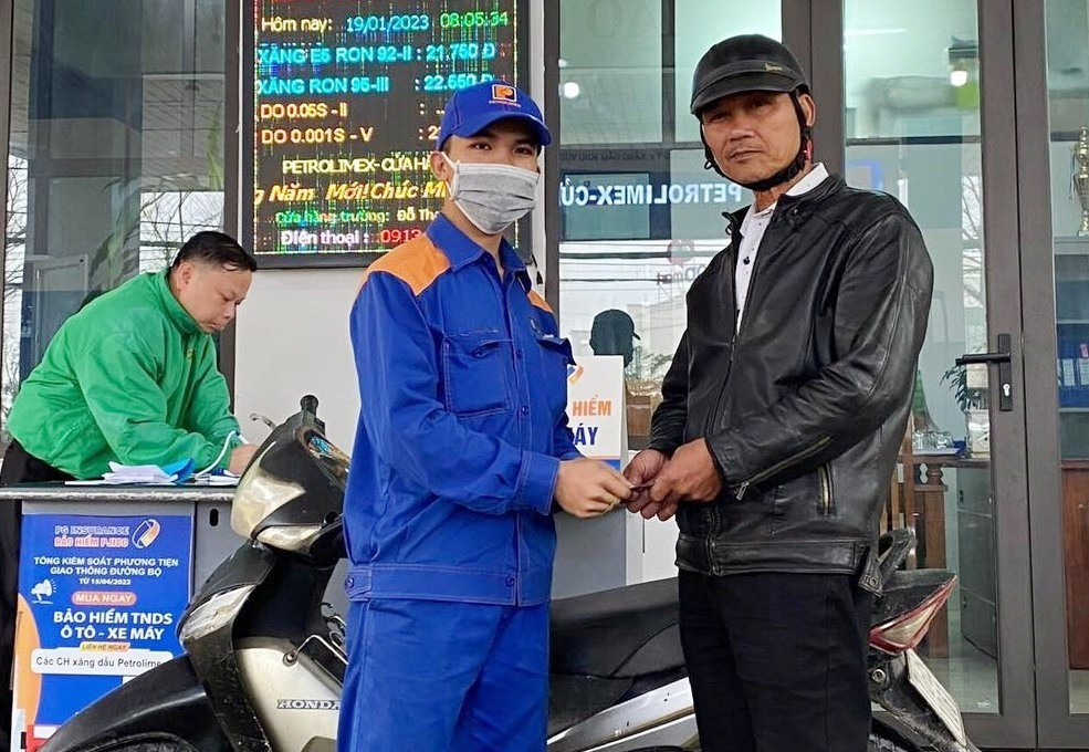 Anh Nguyễn Hữu Trường trao lại sấp tiền cho người bị đánh rơi là ông Huỳnh Trị tại cửa hàng xăng dầu Petrolimex số 48 Phan Châu Trinh, Tam Kỳ. Ảnh:H.N