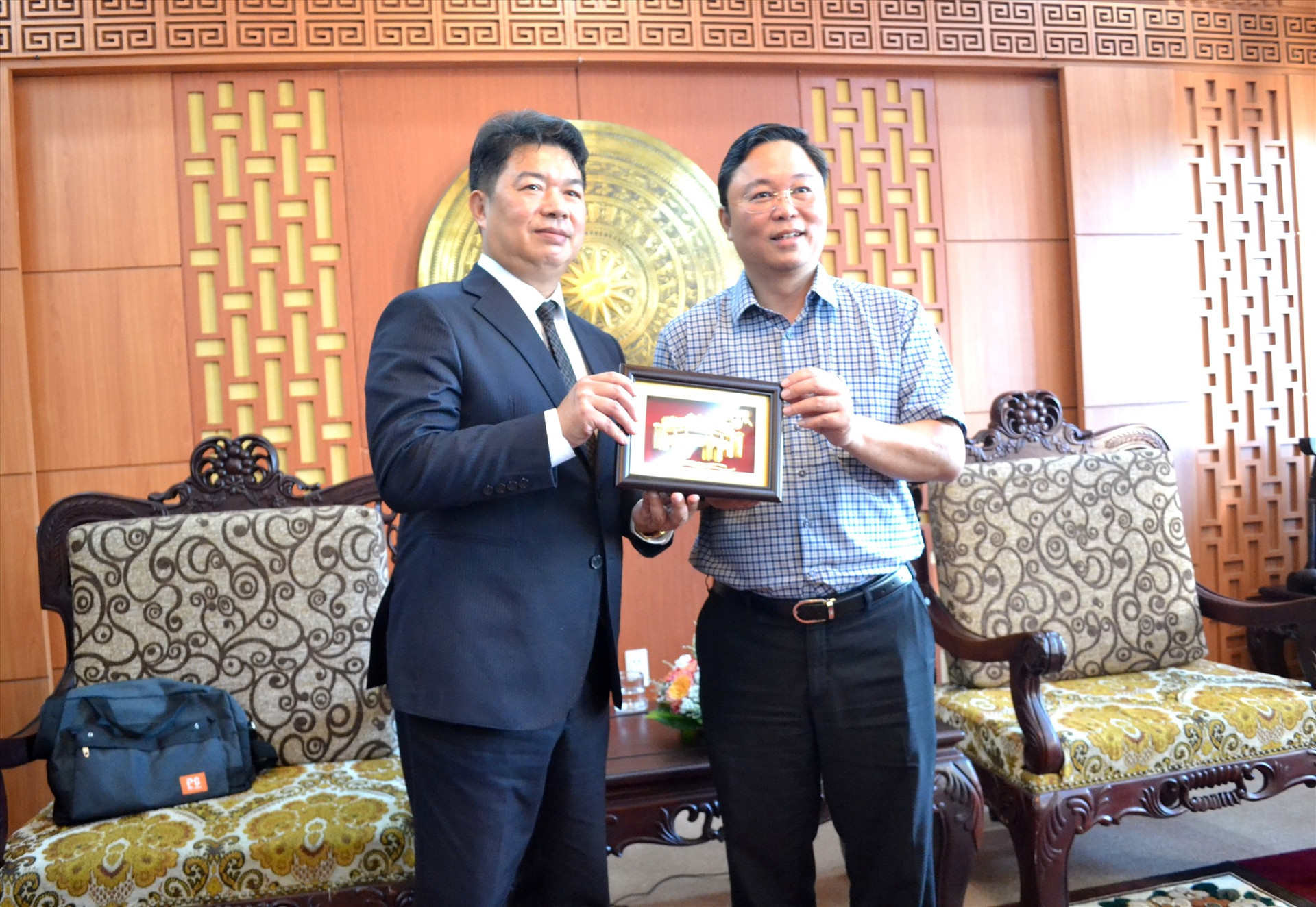 Chủ tịch UBND tỉnh Lê Trí Thanh tặng ông Han Kuo Yao quà đối ngoại là tranh Chùa Cầu 3D mạ vàng. Ảnh: Q.VIỆT