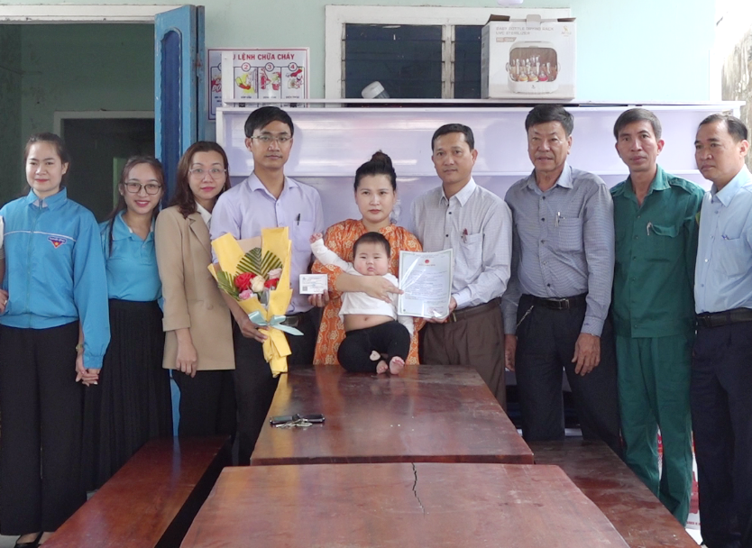 Lãnh đạo thị trấn Hà Lam đến tận nhà trao giấy khai sinh, thẻ BHYT cho cháu Võ Hà Nhi. Ảnh: T.N