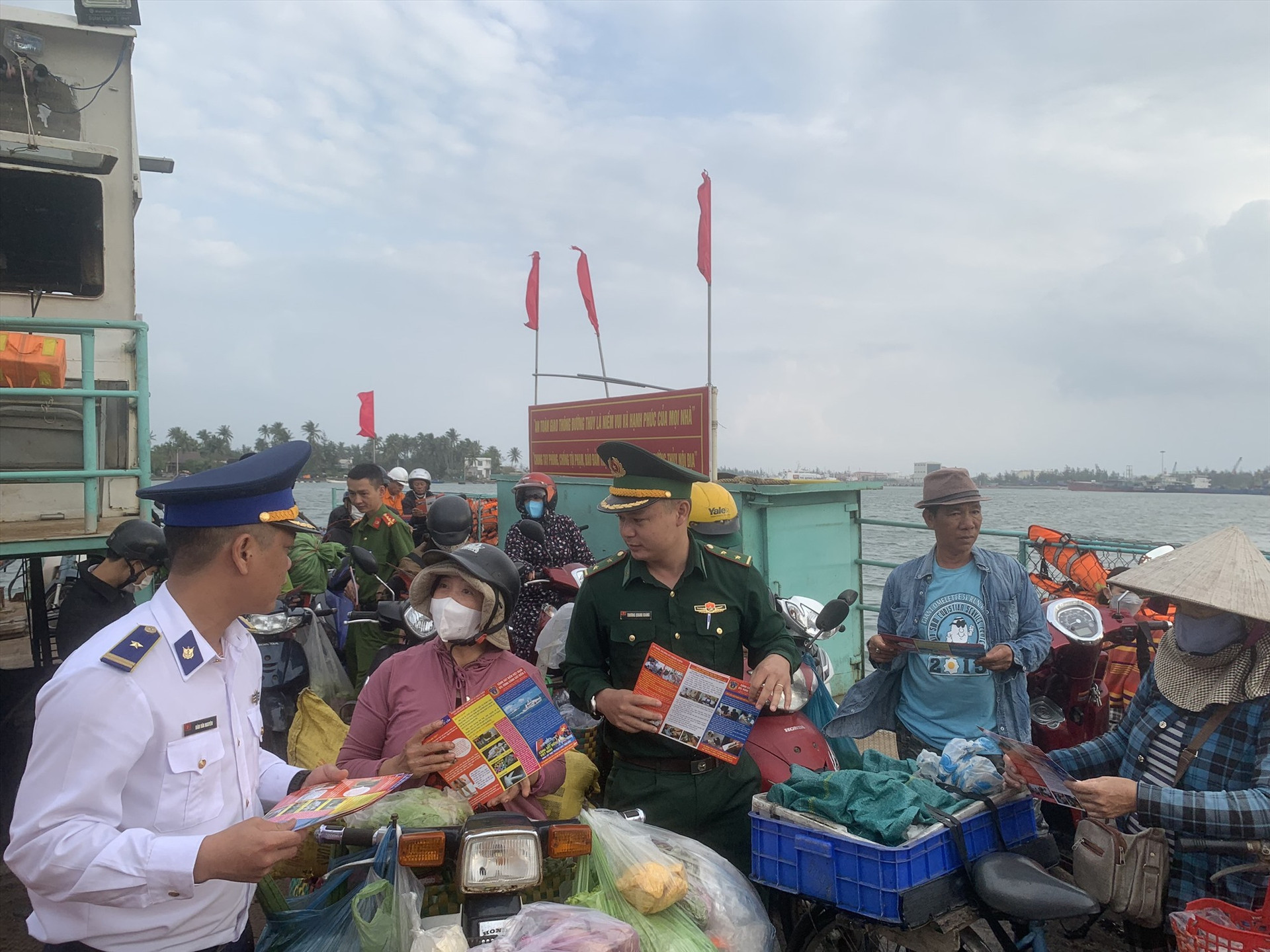 Cán bộ tuyên truyền của Cảnh sát biển cấp phát tờ rơi cho nhân dân khu vực bến phà Tam Hải. Ảnh: P.V