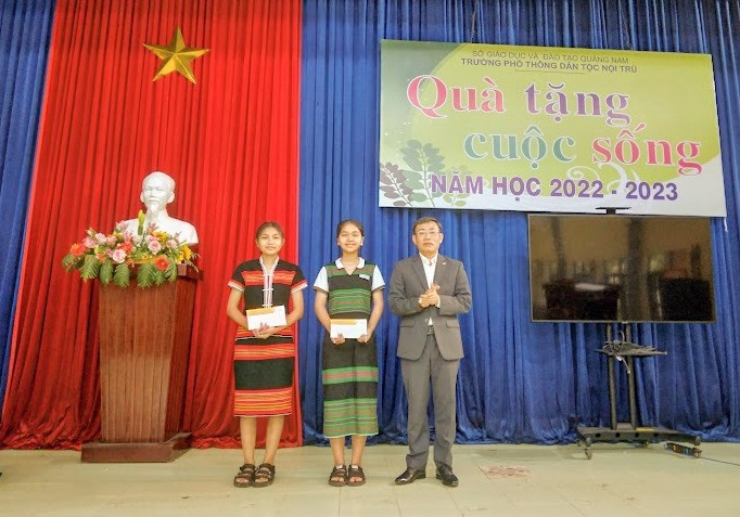 Ông Trần Việt Hùng - Giám đốc Bưu điện Quảng Nam trao học bổng cho em Pơloong Nụ và Zơrâm Danh. Ảnh: BĐ