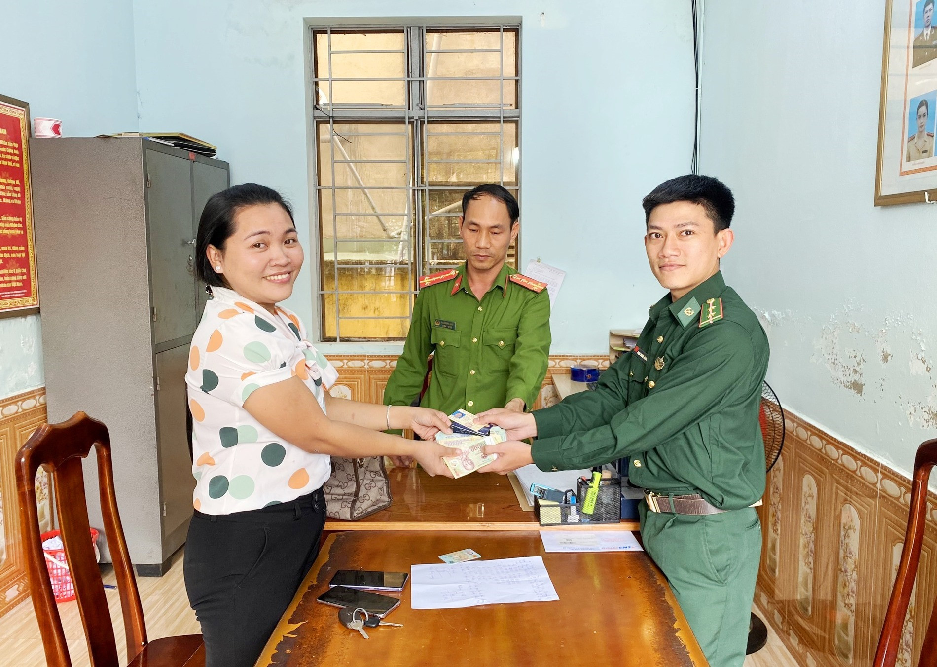 rung úy Phan Hoàng Giang trả lại tiền và giấy tờ cho chị Bùi Thị Ky Na. Ảnh: HỒNG ANH