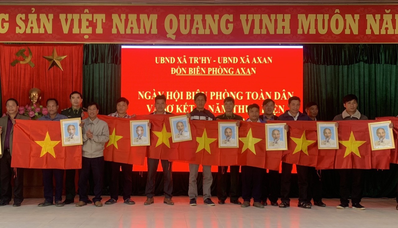 Lãnh đạo UBND huyện Tây Giang và Đồn Biên phòng A Xan tặng  cờ Tổ quốc và ảnh Bác Hồ cho các tổ tự quản. Ảnh: B.P