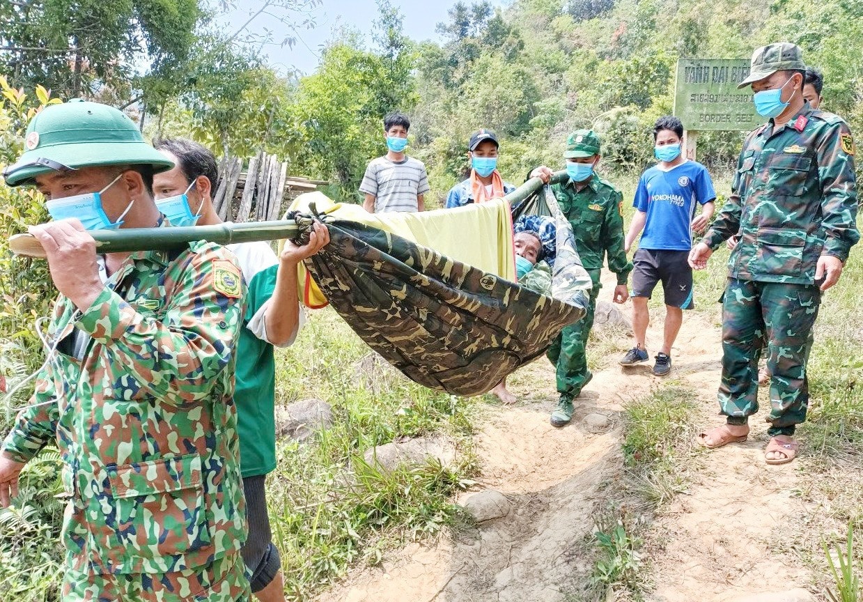 Cán bộ, chiến sĩ Đồn Biên phòng Ga Ry (Tây Giang) vượt đường rừng khiêng cấp cứu một người dân cụm bản A Bưl (huyện Kà Lừm, Sê Kông) bị bệnh nặng gần 1 năm trước. Ảnh: VƯƠNG HOÀNG