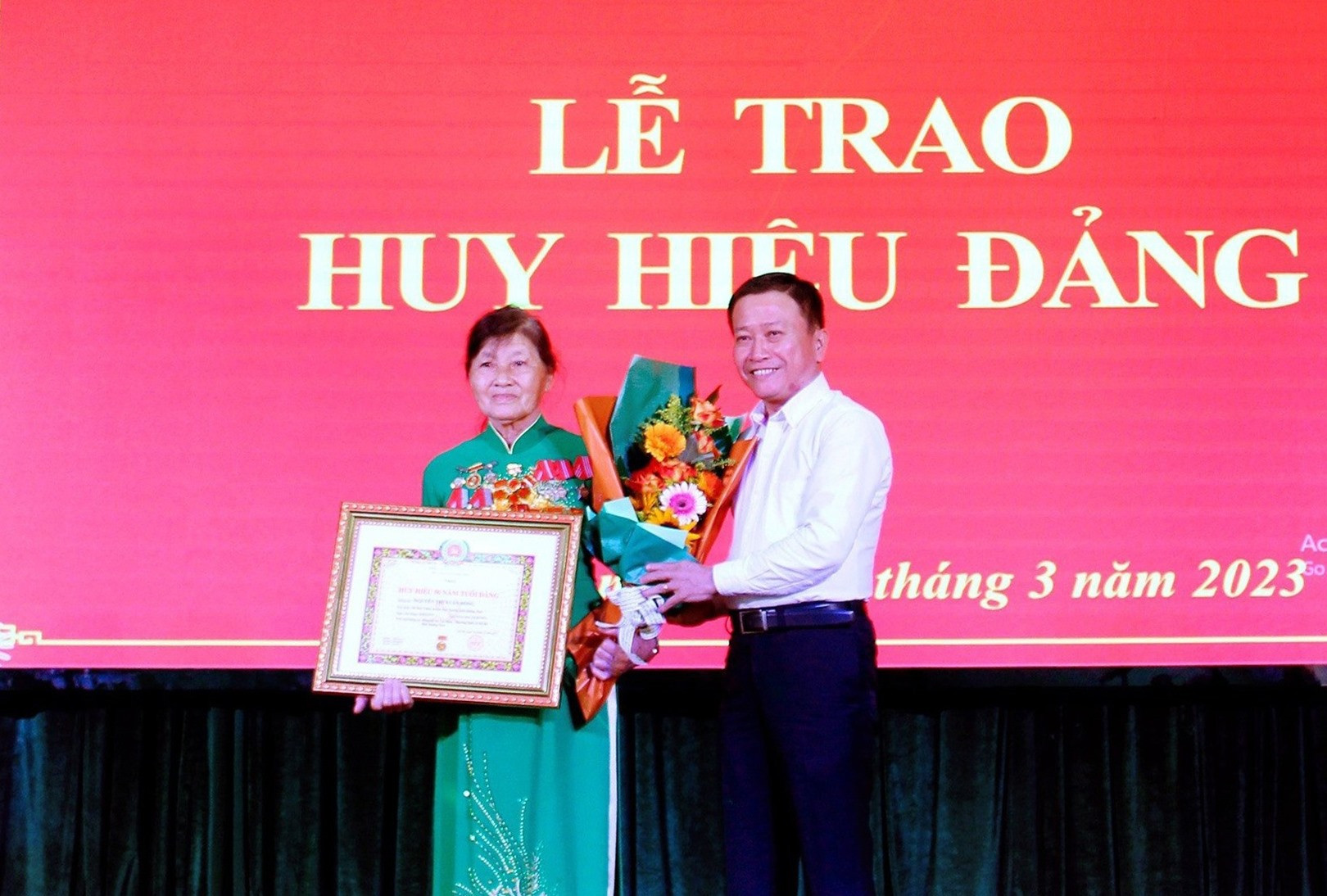 Đồng chí Thái Bình-Tỉnh uỷ viên, Bí thư Đảng ủy Khối các cơ quan tỉnh trao Huy hiệu 50 năm tuổi đảng và hoa chúc mừng đảng viên Nguyễn Thị Xuân Hồng.