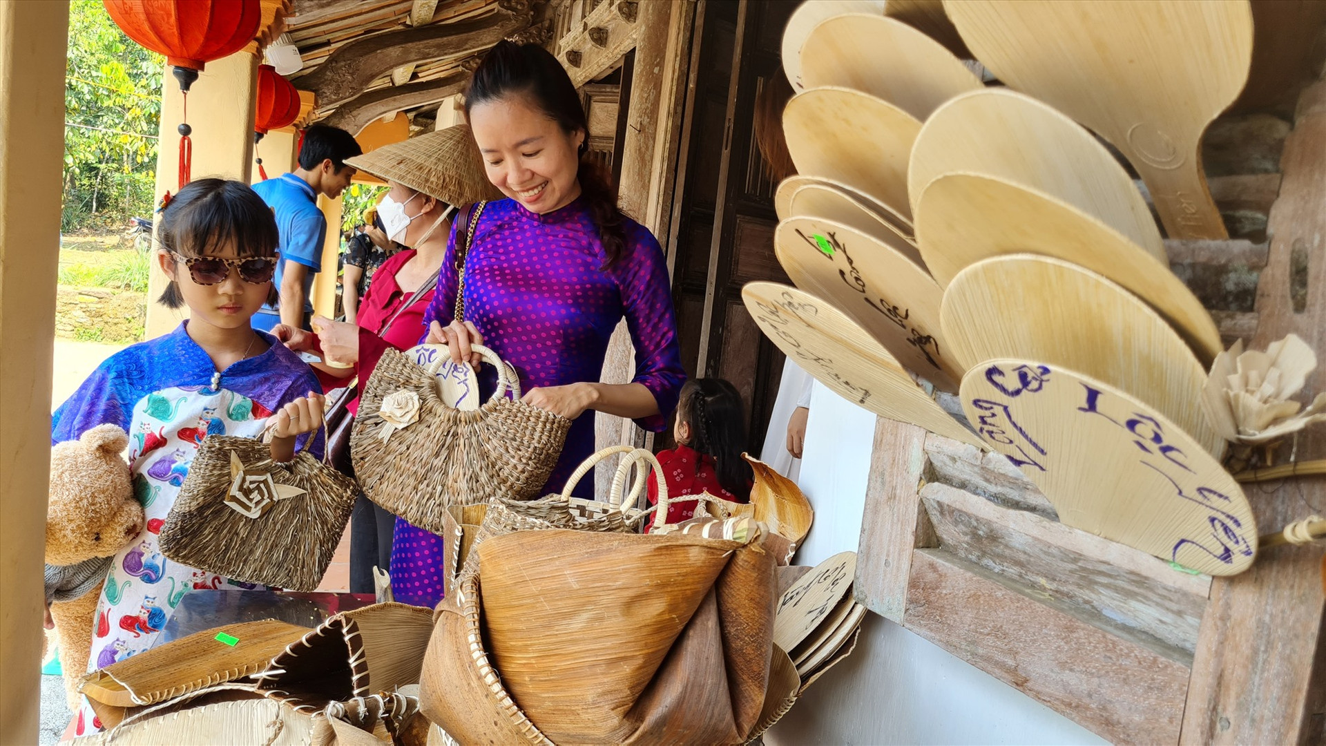 Hai mẹ con một du khách thăm Lộc Yên, thích thú với sản phẩm mo cau truyền thống.