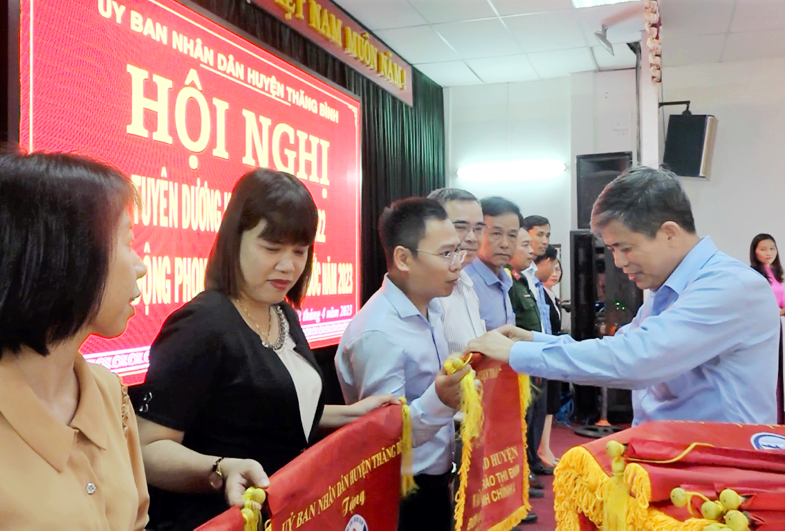 Lãnh đạo huyện Thăng Bình trao cờ cho các tập thể dẫn đầu khối, cụm thi đua của huyện. Ảnh: TÂN NĂM