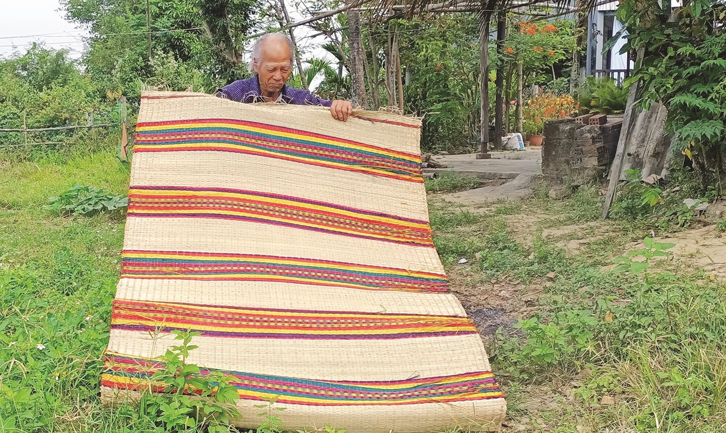 Ông Phạm Phố (80 tuổi, thôn Đông Bình) đem tấm chiếu vừa dệt xong mang ra phơi nắng.