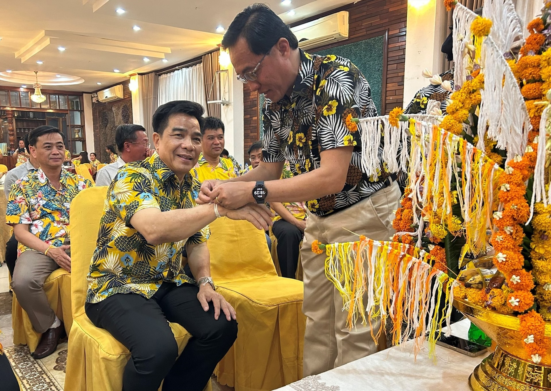 Governor Lechlay Sivilay ties threads around Mr. Dung’s wrist.