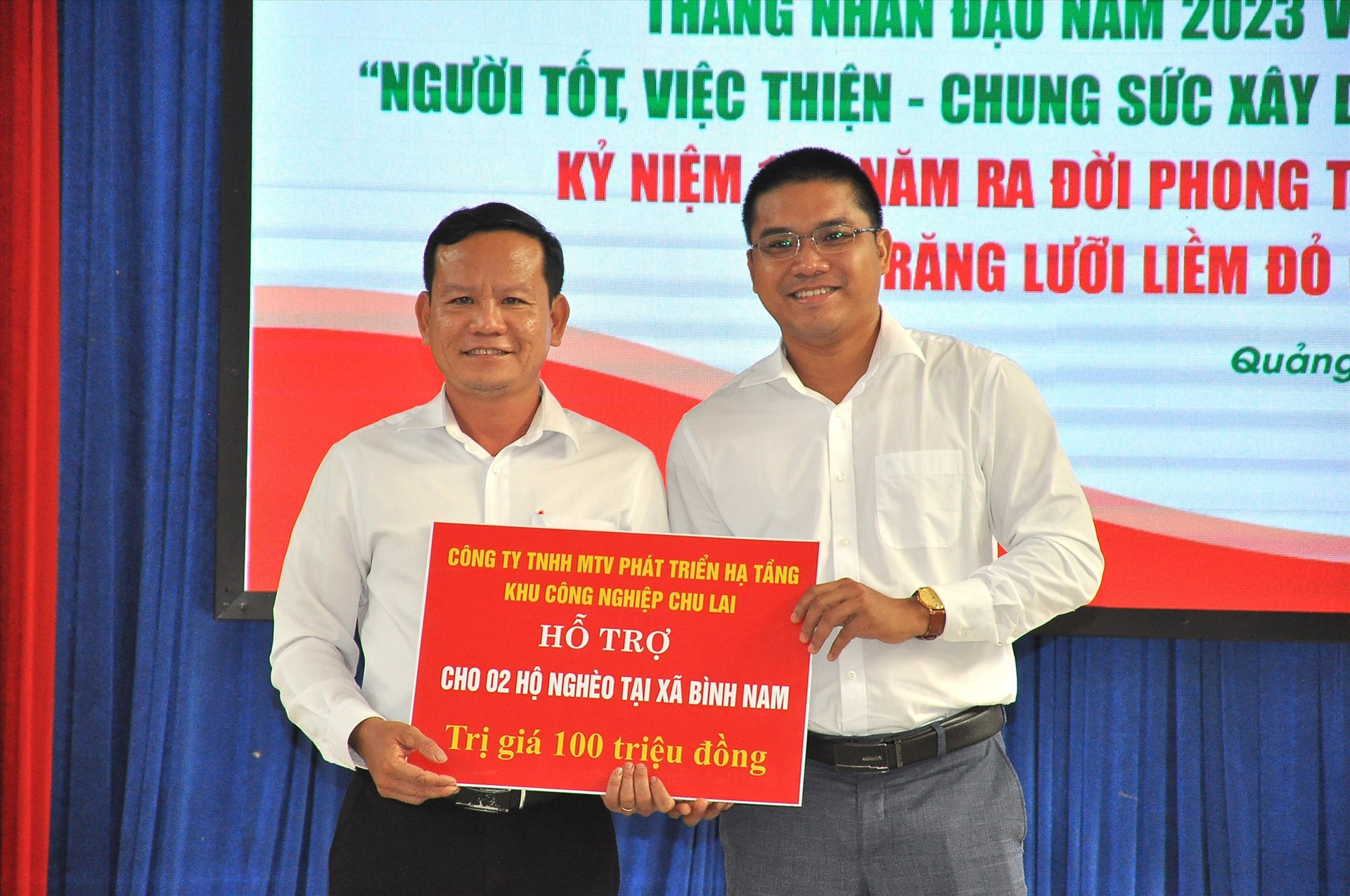 Đại diện Công ty TNHH MTV Phát triển hạ tầng khu công nghiệp Chu Lai hỗ trợ 100 triệu đồng xây dựng nhà ở cho 2 hộ nghèo xã Bình Nam tại lễ phát động Tháng nhân đạo. Ảnh: V.A
