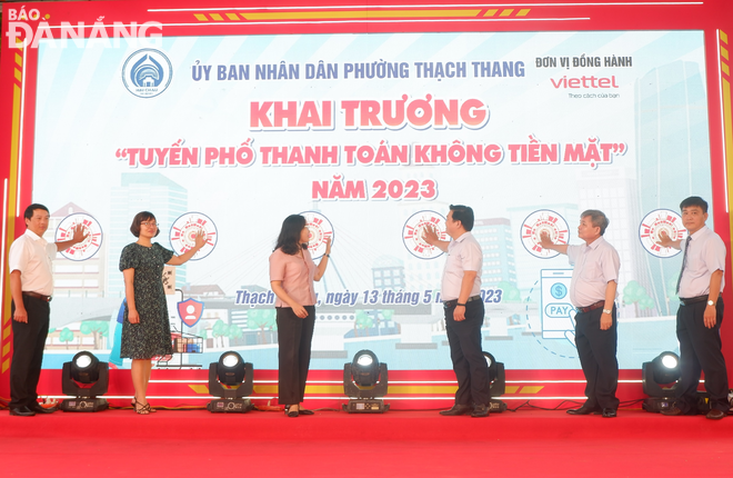 Lãnh đạo UBND quận Hải Châu và UBND phường Thạch Thang bấm nút khai trương tuyến phố thanh toán không tiền mặt. Ảnh: M.Q