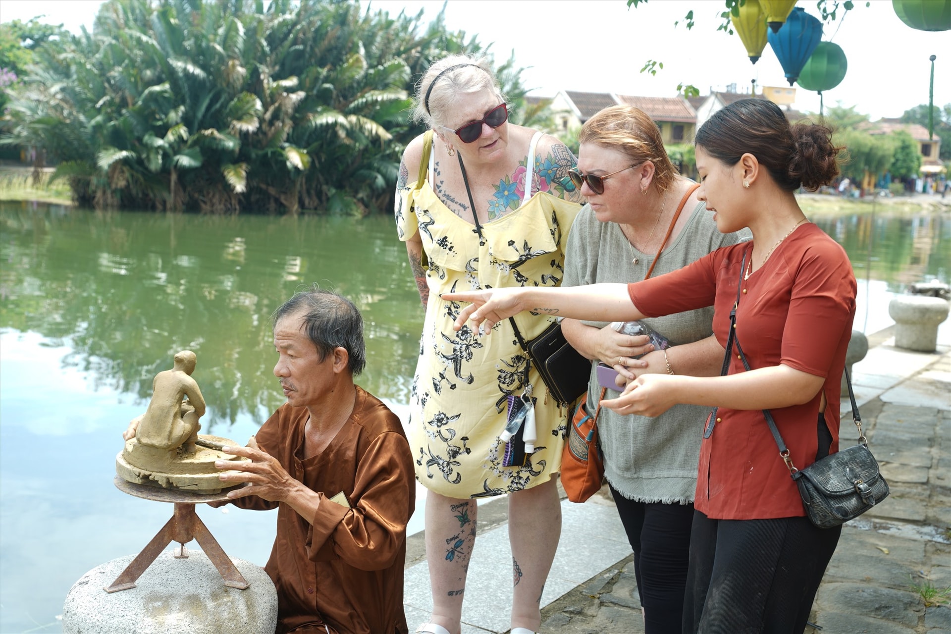 Du khách thích thú tìm hiểu về những sản phẩm thủ công mỹ nghệ truyền thống ở Hội An. Ảnh: Phan Sơn