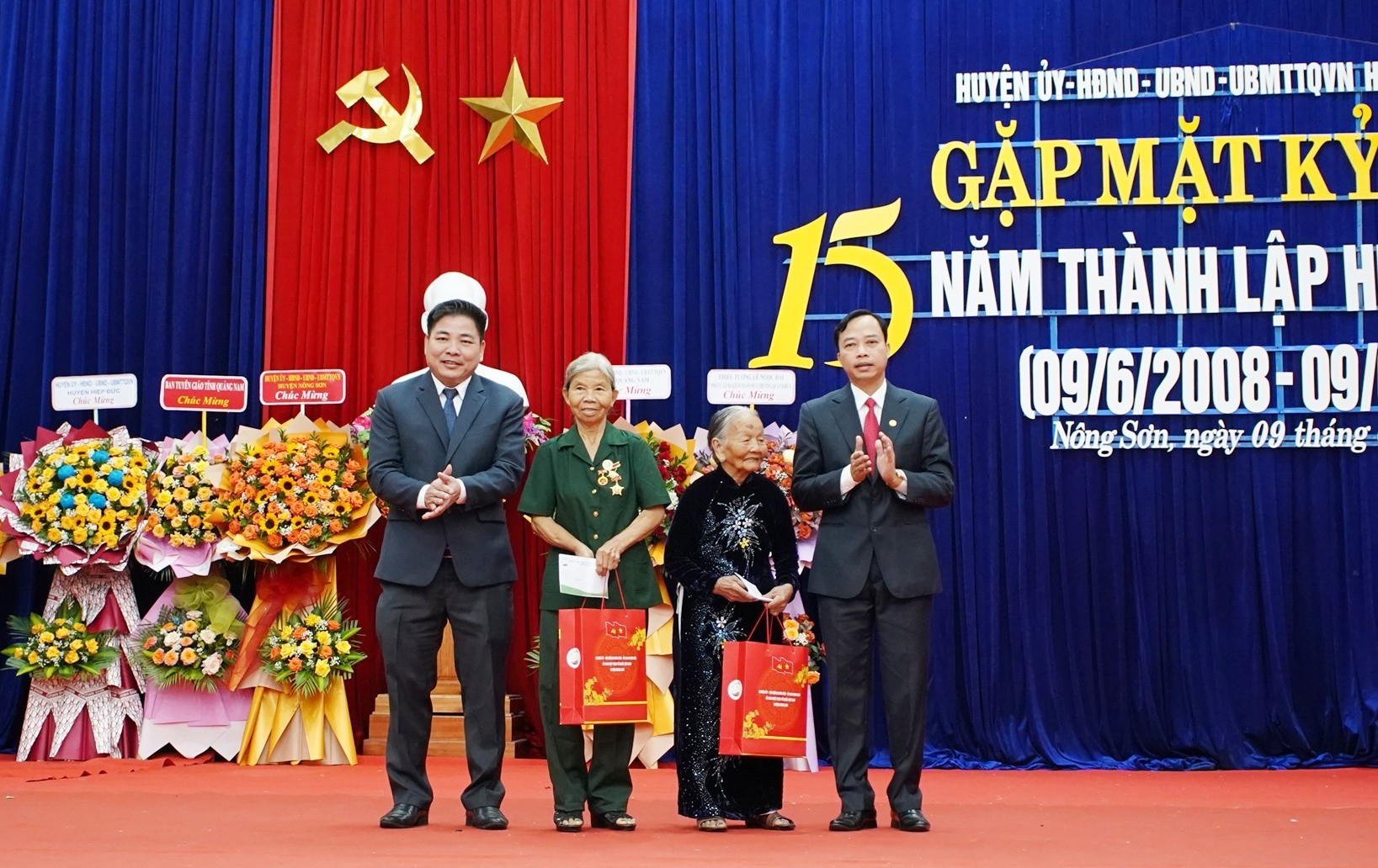 Đại diện Huyện ủy, UBND huyện Nông Sơn trao quà Mẹ VNAH và Anh hùng LLVTND huyện tại lễ gặp mặt. Ảnh: M.T