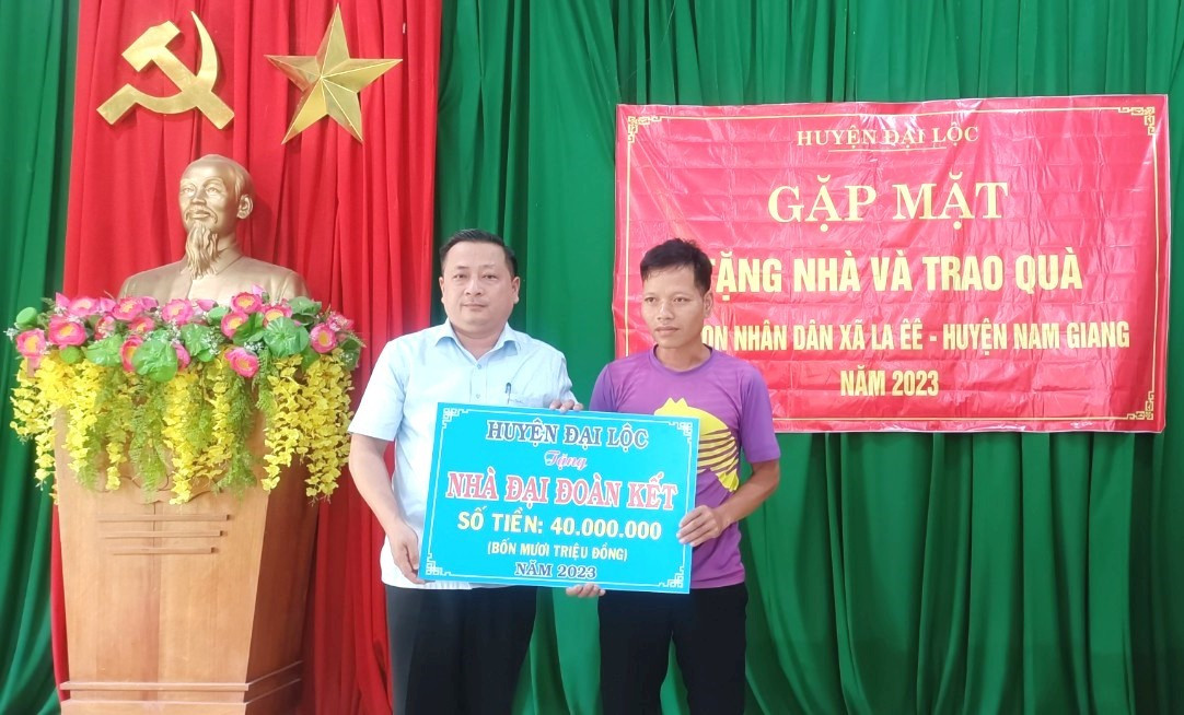 Ông Nguyễn Hảo (đứng bên trái) trao bảng tượng trưng kinh phí hỗ trợ xây dựng nhà đại đoàn kết cho một hộ dân xã La Êê. Ảnh: X.TRINH