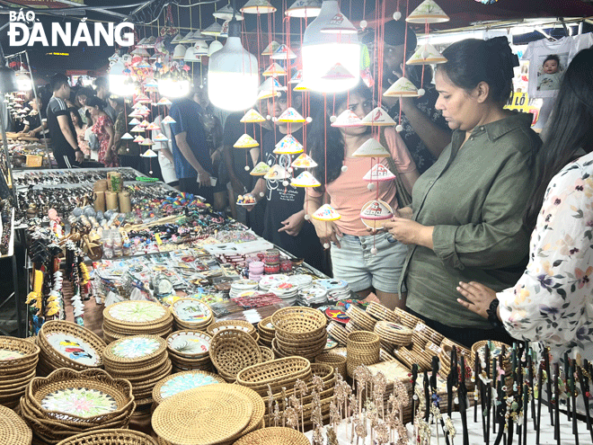 Du khách nước ngoài thích thú với các mặt hàng lưu niệm mang tính đặc trưng của địa phương. Ảnh: D.N
