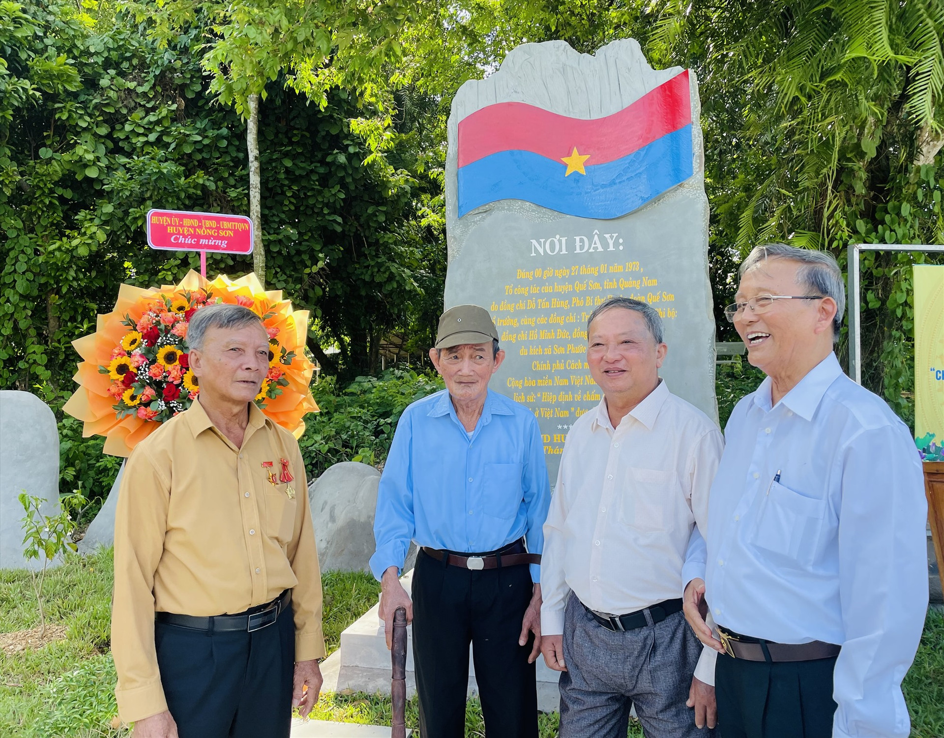 Bốn đồng chí trong tổ công tác ôn lại thời khắc cắm cờ tại Bia di tích lịch sử  “Chốt điểm cắm cờ Chính phủ Cách mạng lâm thời Cộng hòa Miền Nam Việt Nam”. Ảnh: TÂM THÔNG