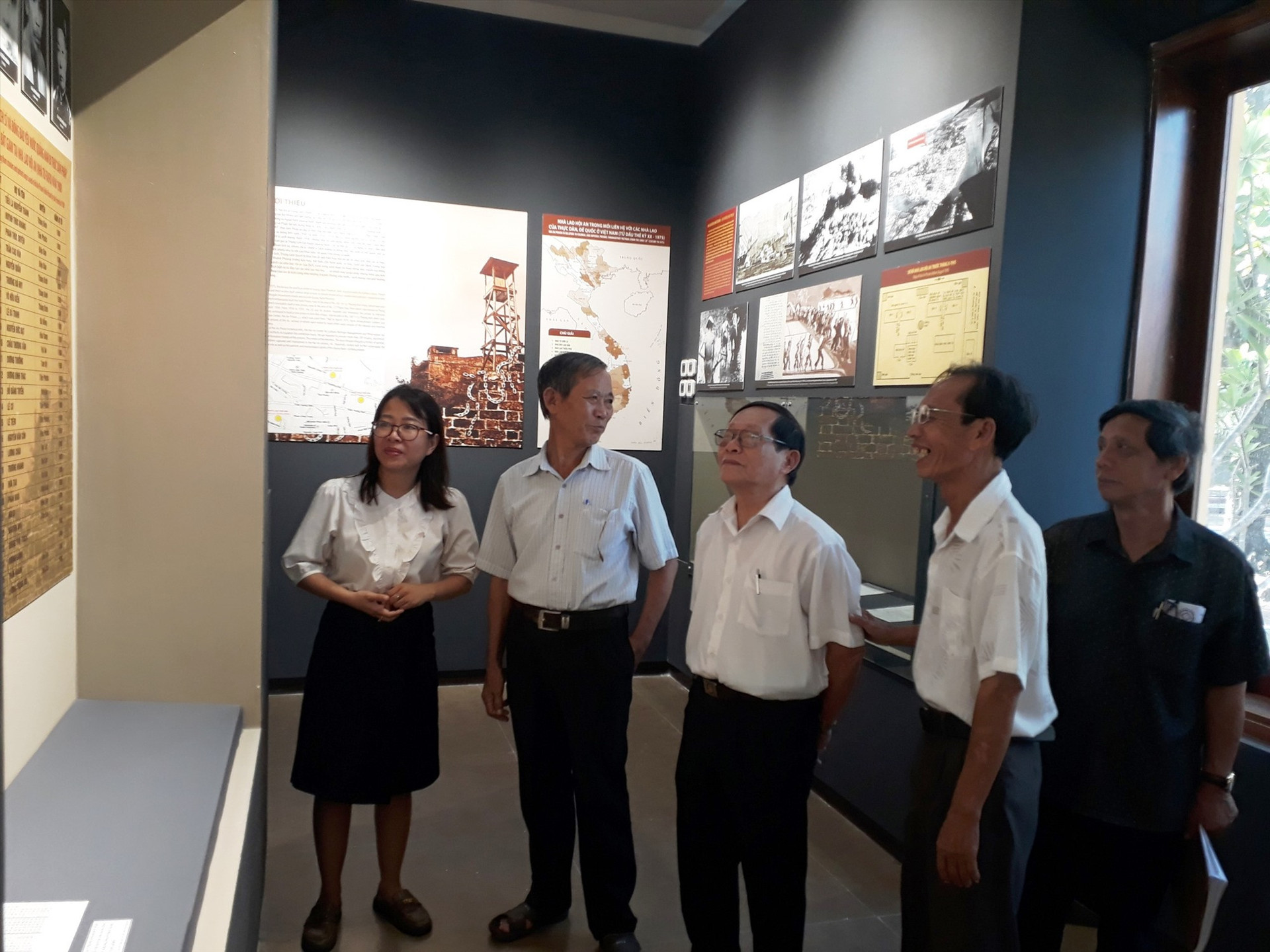 Các đại biểu tù yêu nước nghe giới thiệu tư liệu, hình ảnh lịch sử tại Phòng trưng bày di tích Nhà lao Hội An.