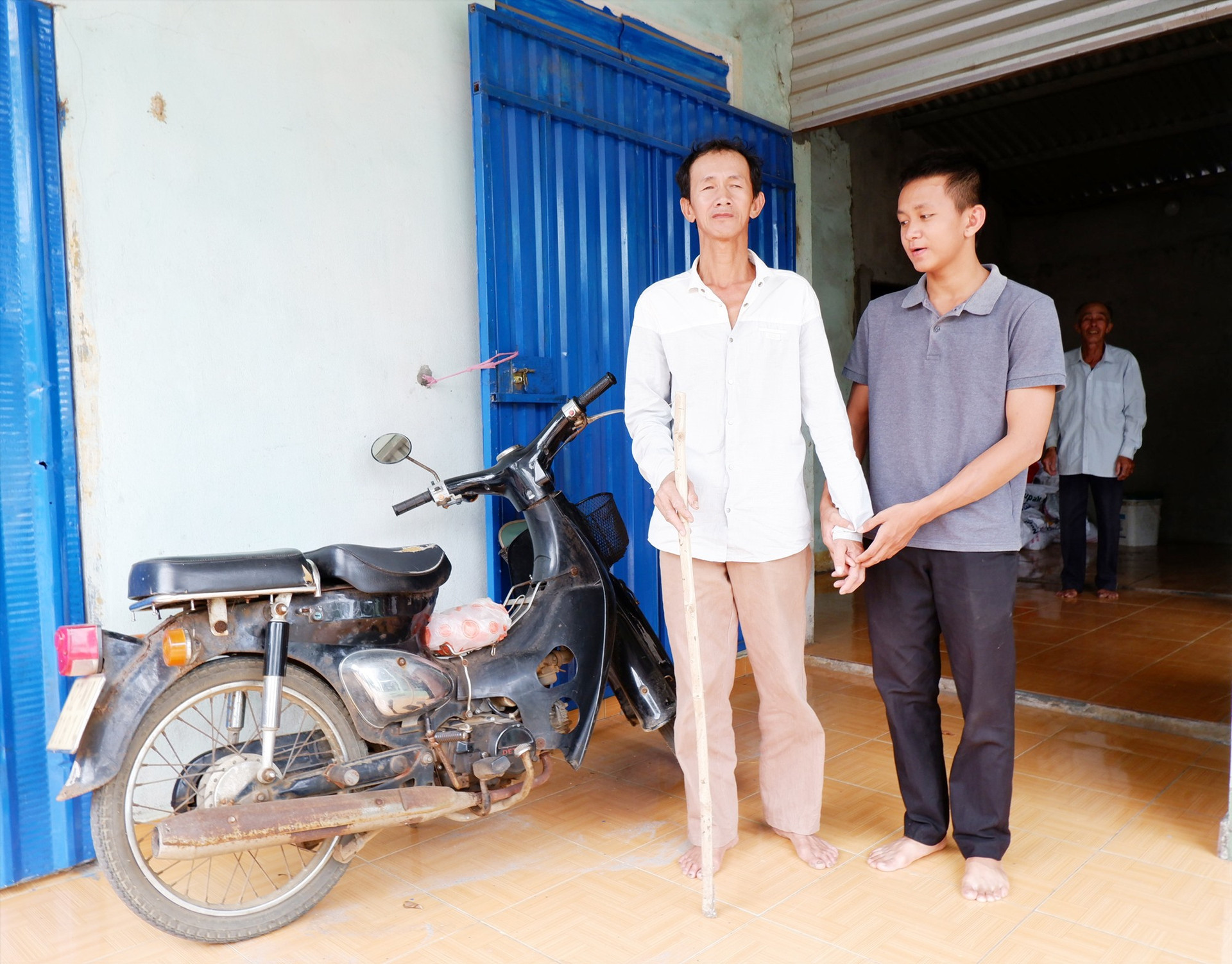 Nguyễn Ngọc Phước và cha, cùng chiếc xe máy cũ kỹ ông nội cho Phước để đi học. Ảnh: X.H