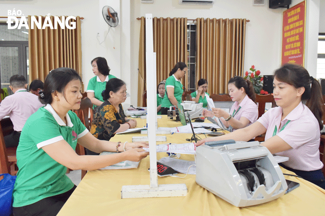 Chị Nguyễn Thị Bé (bên trái), Tổ trưởng tổ tiết kiệm và vay vốn phụ trách tổ dân phố 18 và 20 phường Bình Thuận (quận Hải Châu) nộp lãi và gốc cho các tổ viên vay vốn của Ngân hàng Chính sách xã hội thành phố. Ảnh: X.D
