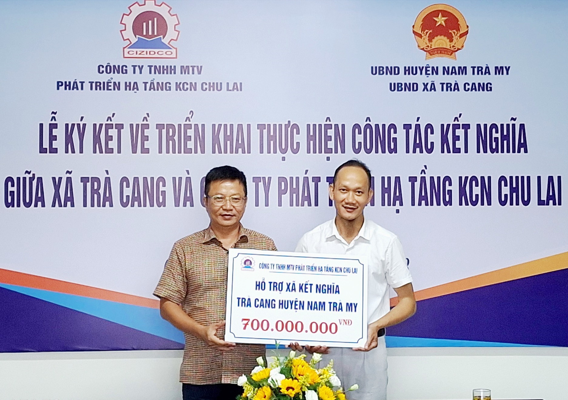 Ông Lê Ngọc Thủy -Giám đốc CIZIDCO (bên trái) trao tượng trưng kinh phí 700 triệu đồng cho Chủ tịch UBND xã Trà Cang Ngô Tấn Lạc. Ảnh NTB