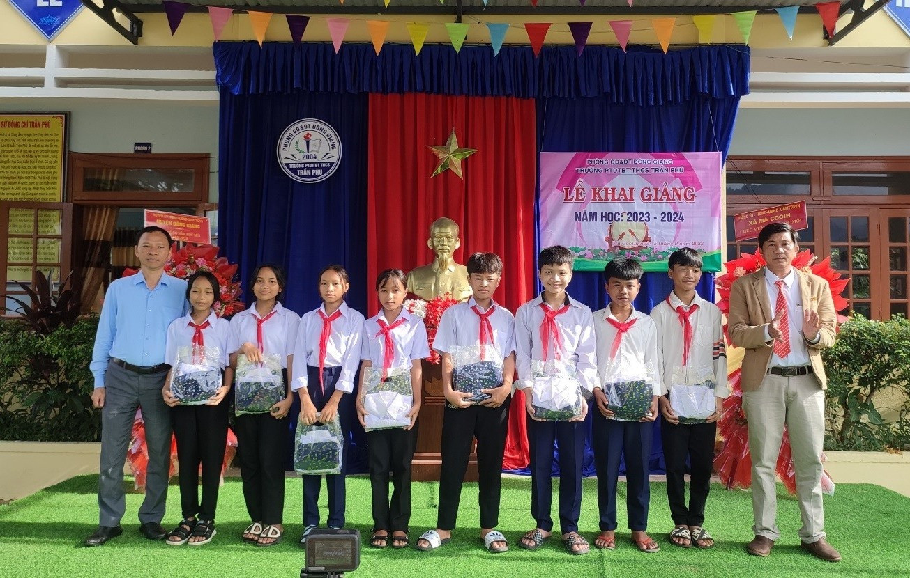 Đại điện Công ty CP Thủy điện A Vương trao tặng áo quần đồng phục cho các em học sinh Trường THCS bán trú Trần Phú, xã Mà Cooih tại lễ khai giảng. Ảnh: V.L