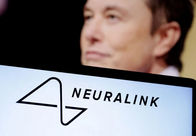 Logo Neuralink hiển thị trên màn hình một chiếc laptop, đằng sau là hình ảnh Elon Musk. Ảnh: Reuters
