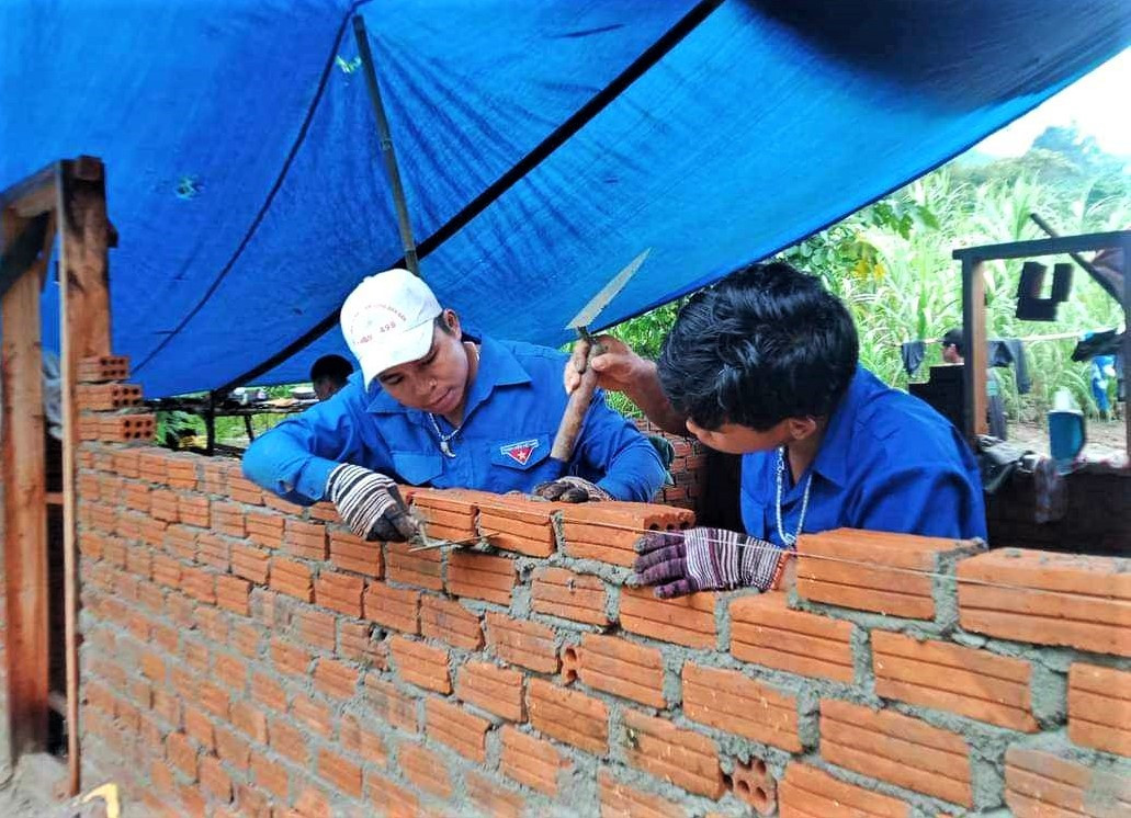 Bh’nướch Báo (bên trái) cùng nhóm thợ xây giúp dân dựng nhà ở.