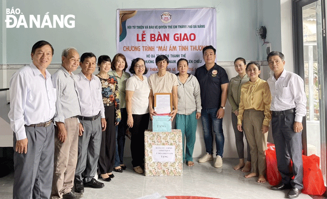 Vợ chồng chị Trần Thị Thanh Thế (37 tuổi, trú tổ 51 phường Hòa Hiệp Nam - đứng thứ 5 bên phải sang) tại buổi nhận bàn giao căn nhà “Mái ấm tình thương”. Ảnh: ĐẮC MẠNH