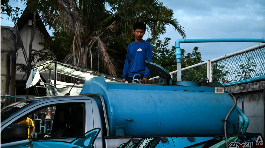 Các thanh niên trẻ làm việc với xe bồn chứa nước (Ảnh: Jack Board/CNA)