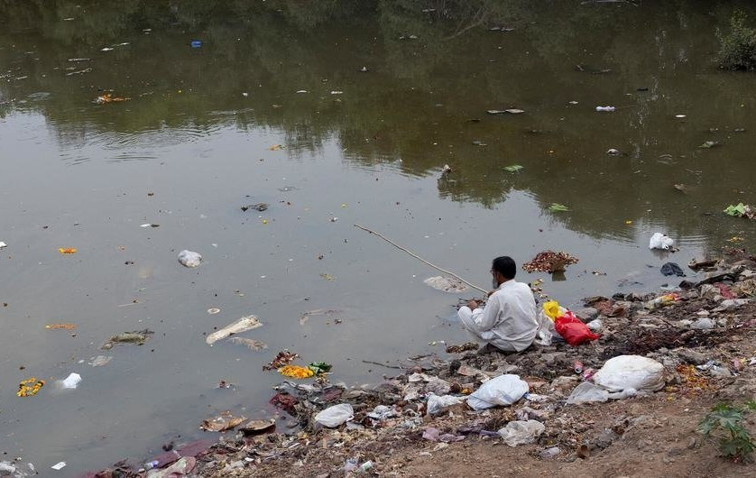 Một người đàn ông câu cá trên bờ sông Mithi ở miền Tây Ấn Độ - nơi trở thành bãi chứa dầu cặn và hóa chất độc hại. Ảnh: UNICEF