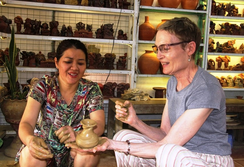 A foreign visitor learns about the process of making pottery products at Thanh Ha pottery village. Photo: daidoanket.vn