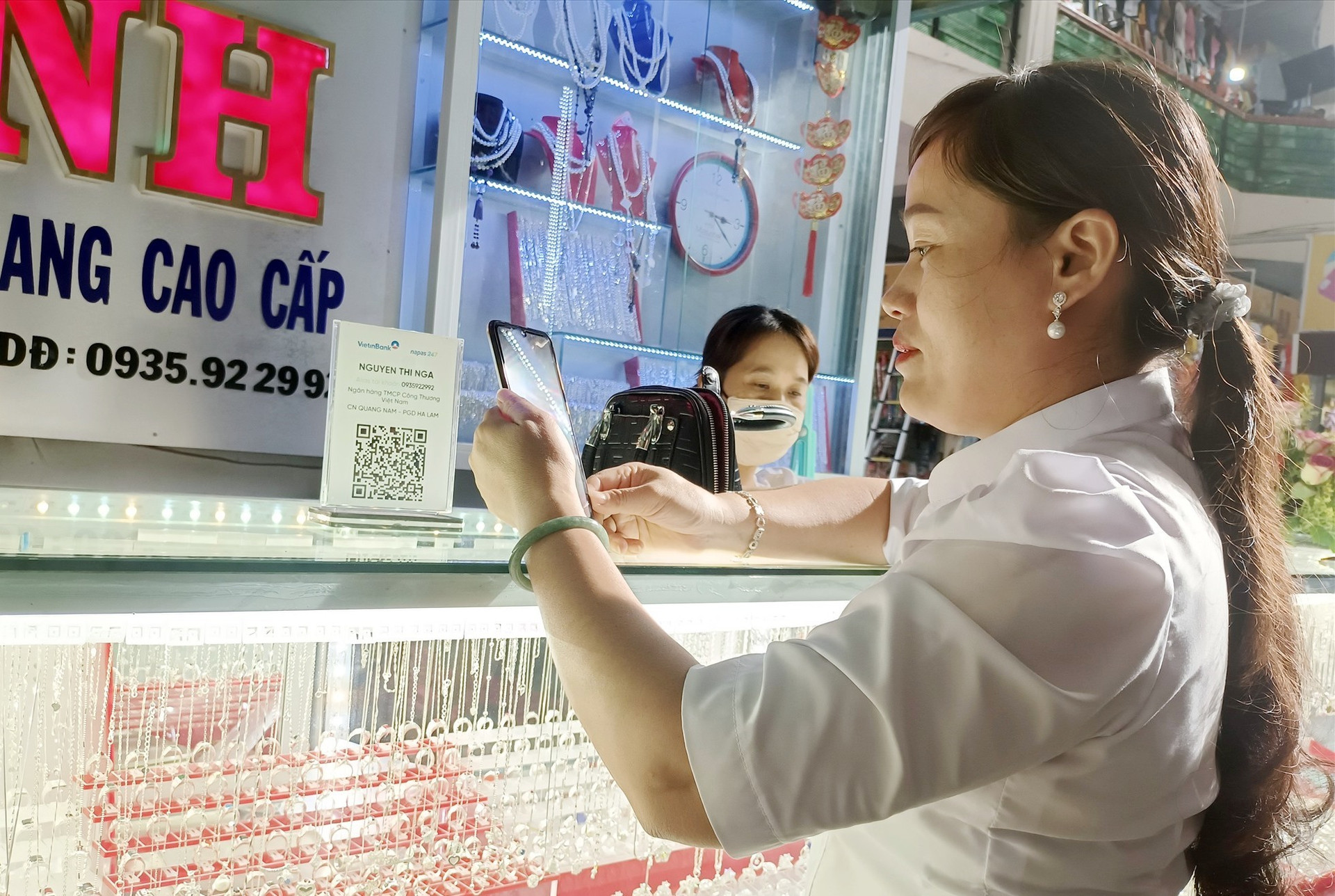 Khách hàng thực hiện quét mã thanh toán tiền qua tài khoản ngân hàng khi mua hàng tại chợ Nam Phước.