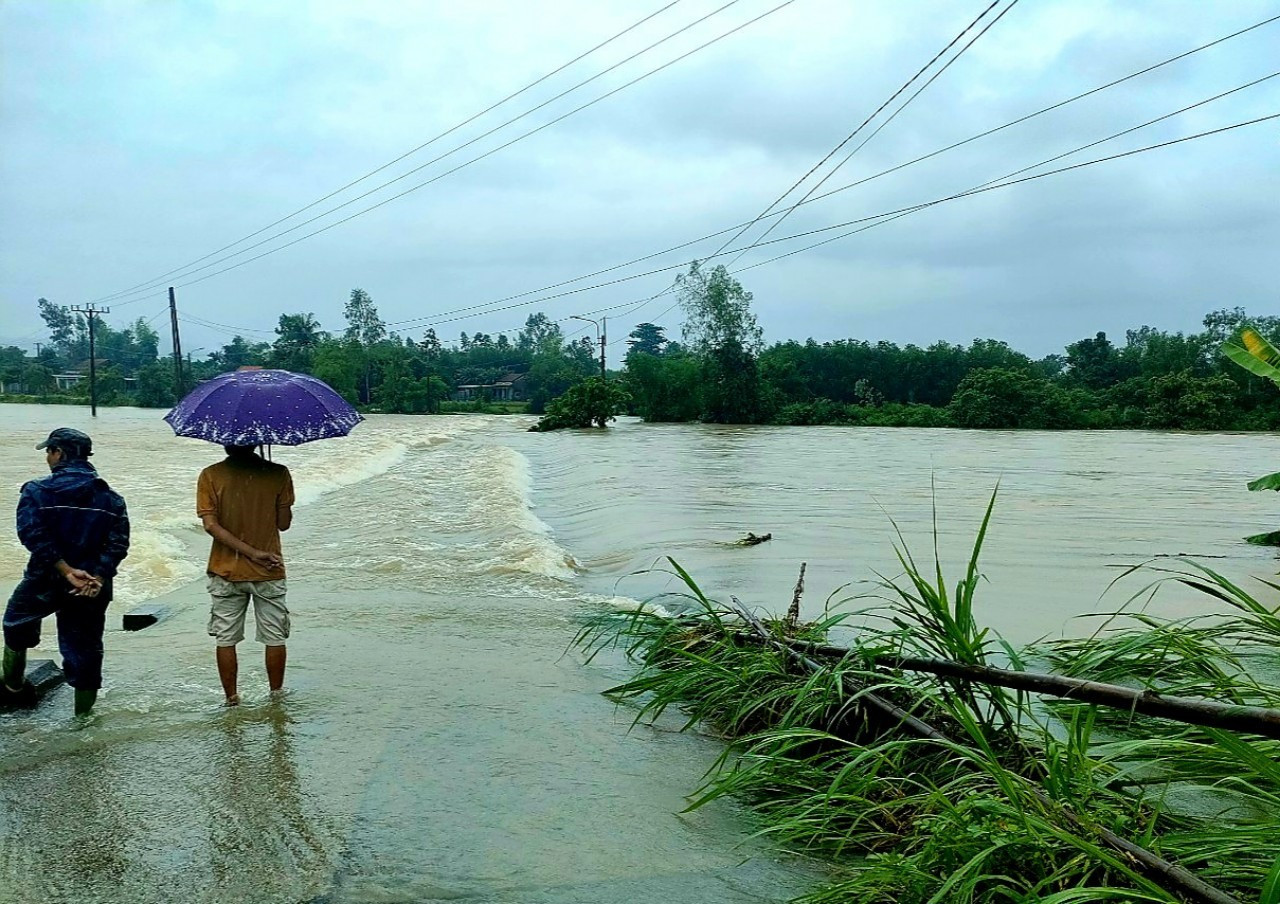 Mưa lớn kéo dài, nước sông dâng cao khiến tuyến đường từ thị trấn Đông Phú đi xã Quế Minh bị ngập sâu, nước chảy mạnh.       Ảnh: PV