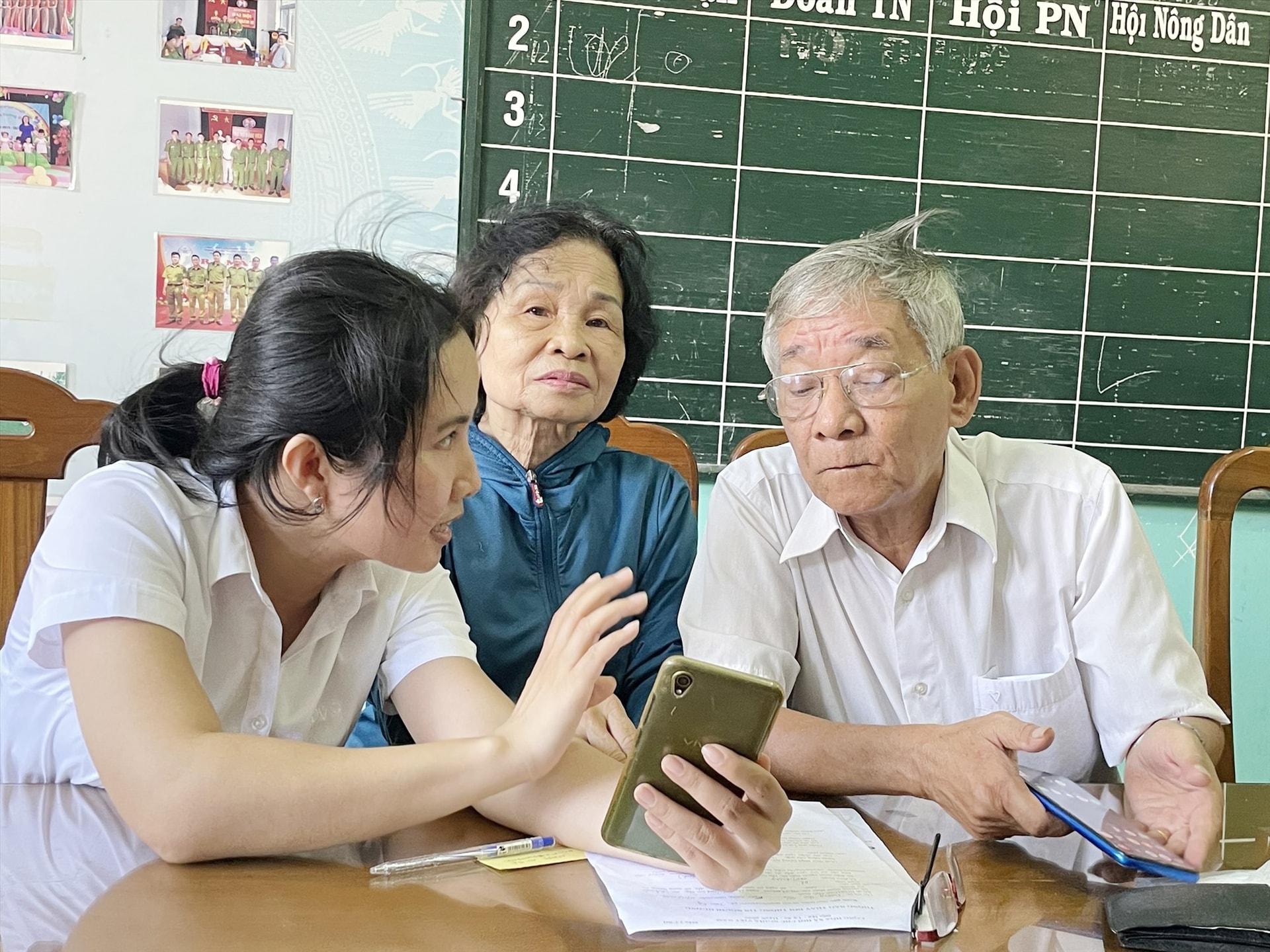 Nhân viên ngân hàng BIDV Quảng Nam hướng dẫn người có công của phường Phước Hòa sử dụng tài khoản. Ảnh: T.X