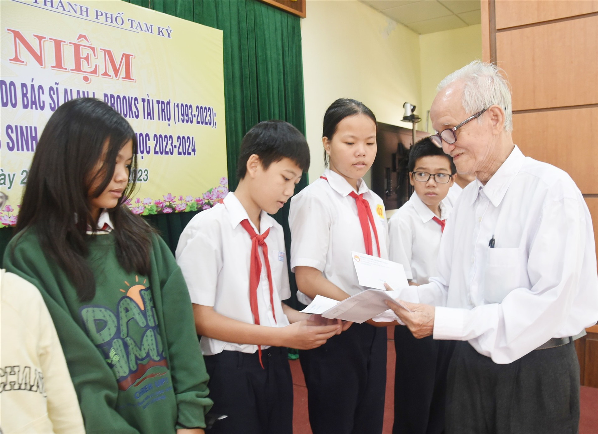Thầy giáo Huỳnh Văn Luận thay mặt bác sĩ Alan L. Brooks trao học bổng cho học sinh Tam Kỳ năm 2023. Ảnh: X.P