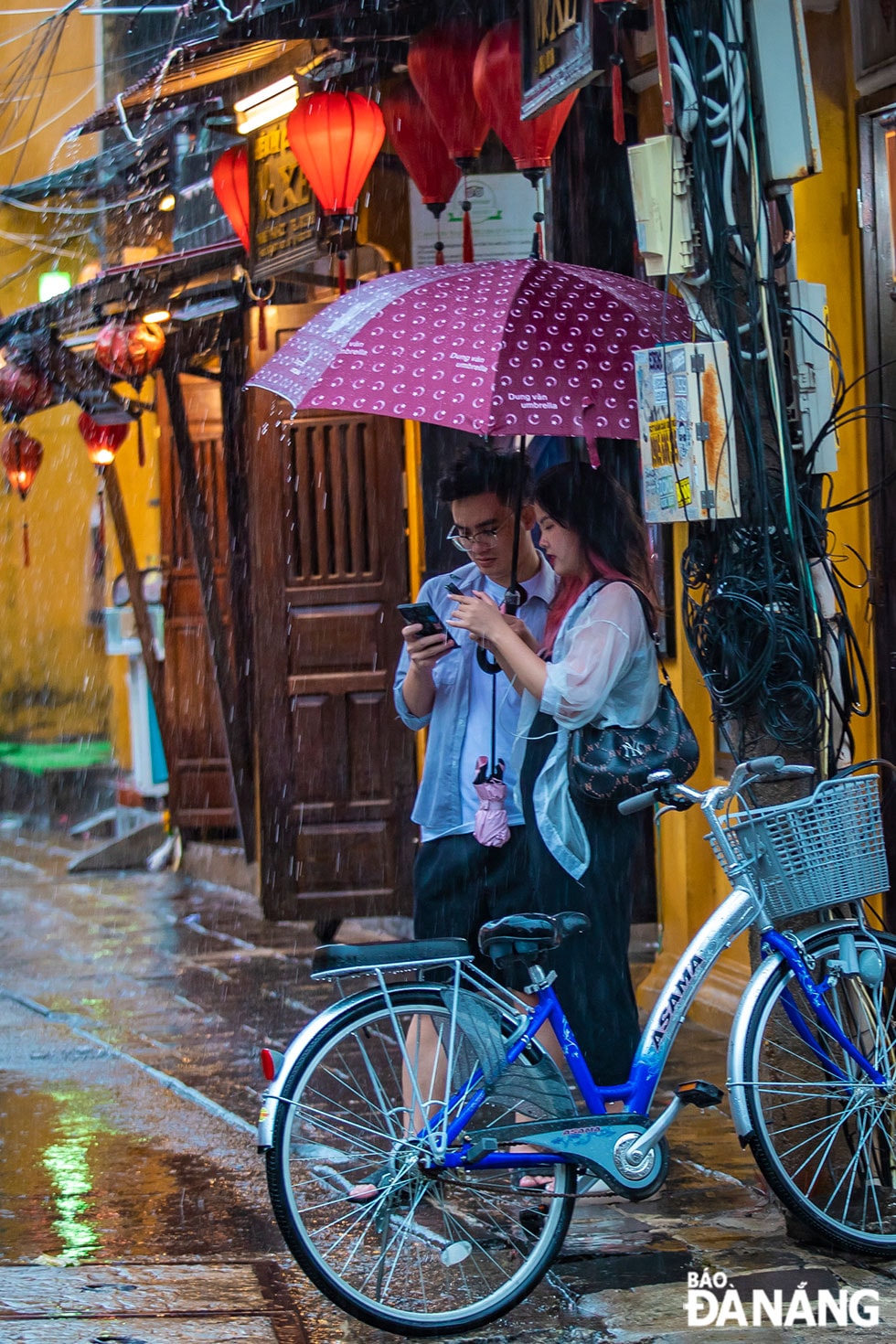 Đôi bạn đứng bên mái hiên chờ cơn mưa ngớt hạt.