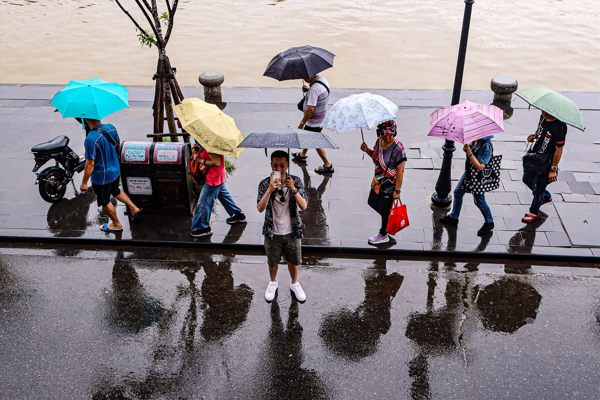 Cầm dù đội mưa chụp lại khoảnh khắc mưa nắng trên phố cổ Hội An.