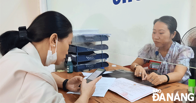 Công chức tư pháp - hộ tịch phường Thạch Thang (quận Hải Châu) hướng dẫn công dân đăng ký và thực hiện dịch vụ công trực tuyến toàn trình đối với nhóm thủ tục liên thông đăng ký khai sinh - đăng ký thường trú - cấp thẻ bảo hiểm y tế cho trẻ em dưới 6 tuổi. Ảnh: TRỌNG HUY