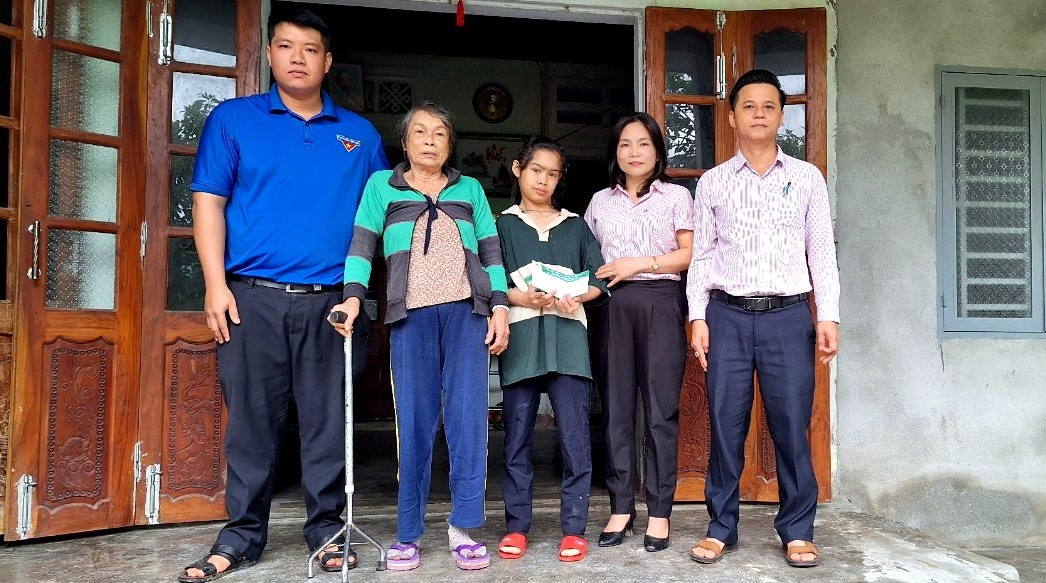 Ngân hàng CSXH huyện Quế Sơn thăm hỏi, tặng quà em Trần Thị Diệu Trinh (ở giữa). Ảnh: Q.VIỆT