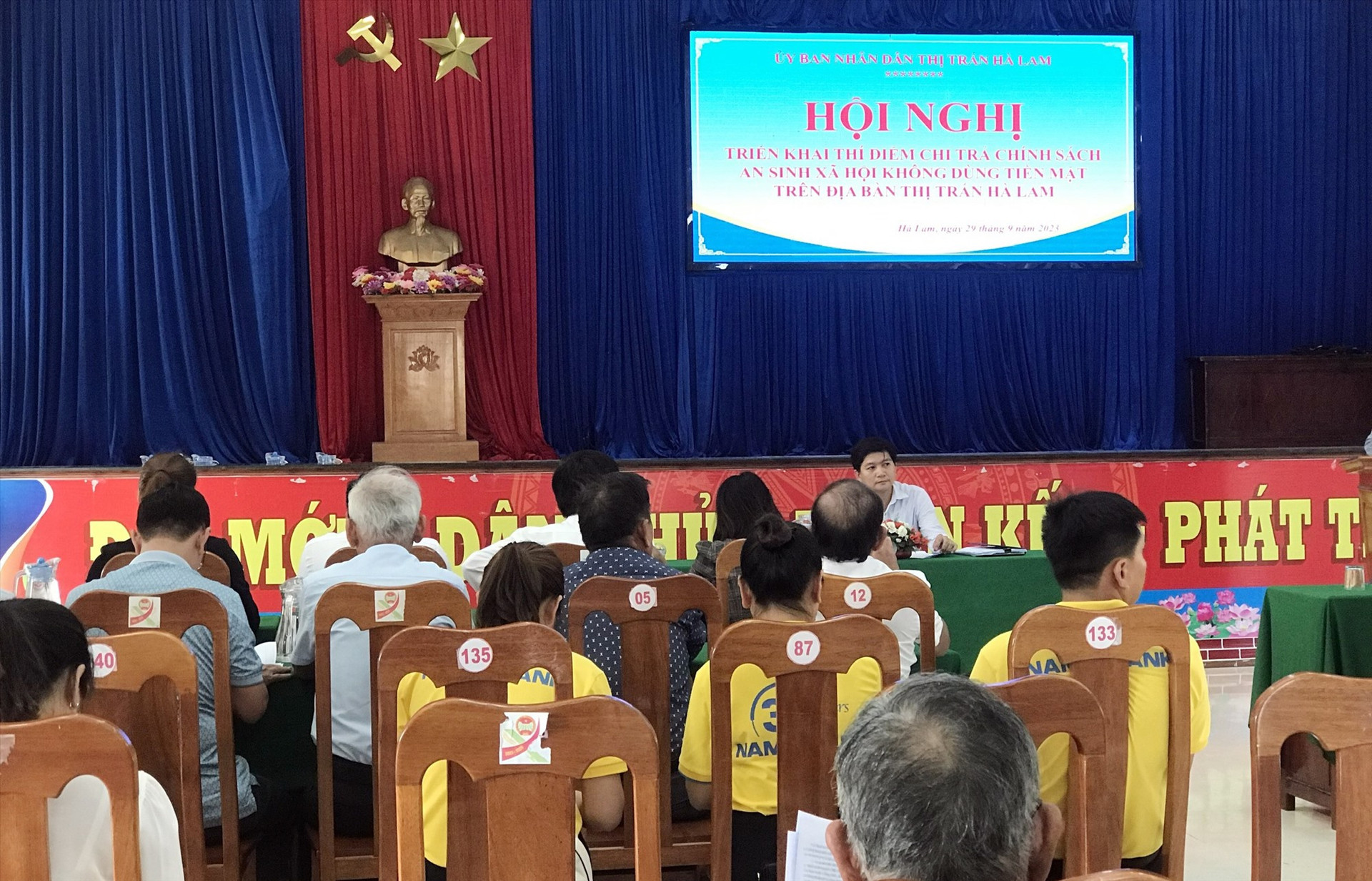 Hội nghị triển khai phương án thí điểm chi trả chính sách ASXH không dùng tiền mặt tại thị trấn Hà Lam. (Ảnh T-N)