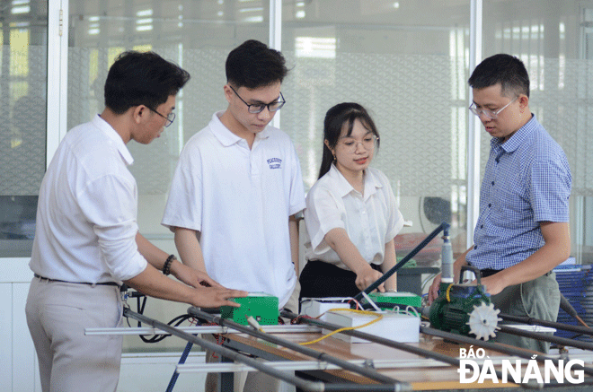 Tiến sĩ Phạm Thanh Phong (bên phải) và các sinh viên nghiên cứu mô hình thiết kế “Thiết bị chẩn đoán và giám sát vị trí điểm rò rỉ trong hệ thống đường ống dẫn chất lỏng”. Ảnh: V.D
