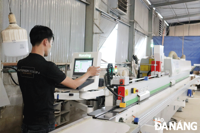 Công nhân vận hành máy dán cạnh tự động tại Công ty CP Thiết kế mỹ thuật P.A.D.  Ảnh: TRẦN TRÚC