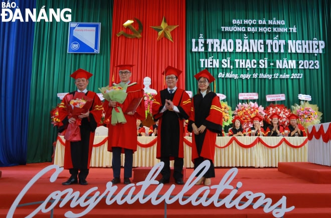 Lãnh đạo nhà trường trao bằng cho tân tiến sĩ (thứ hai từ trái qua). Ảnh: NGỌC HÀ
