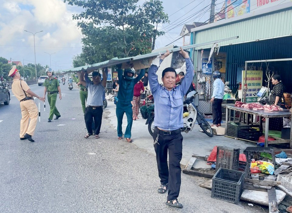 Lực lượng chức năng tháo dỡ tôn lấn chiếm hành lang an toàn giao thông.