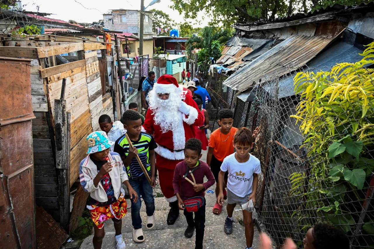 Một người đàn ông hóa trang thành ông già Noel cùng trẻ em đi dạo trên đường phố Havana, Cuba, vào ngày 21 tháng 12 năm 2023. (YAMIL LAGE/AFP qua Getty Images) ​